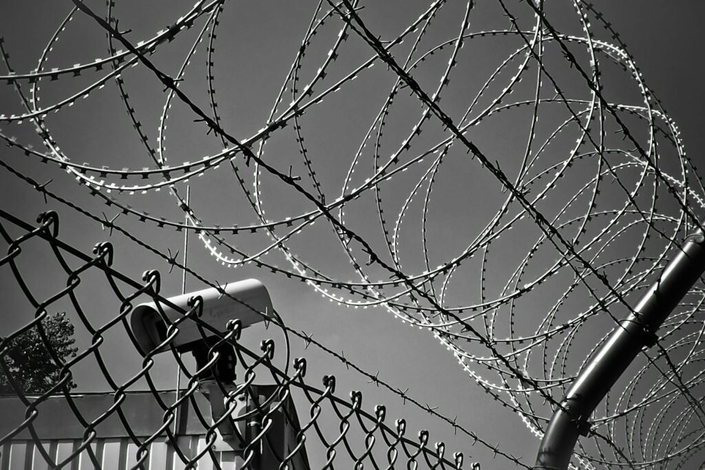 A black and white image featuring barbed wire and a security camera, symbolizing protection and surveillance.