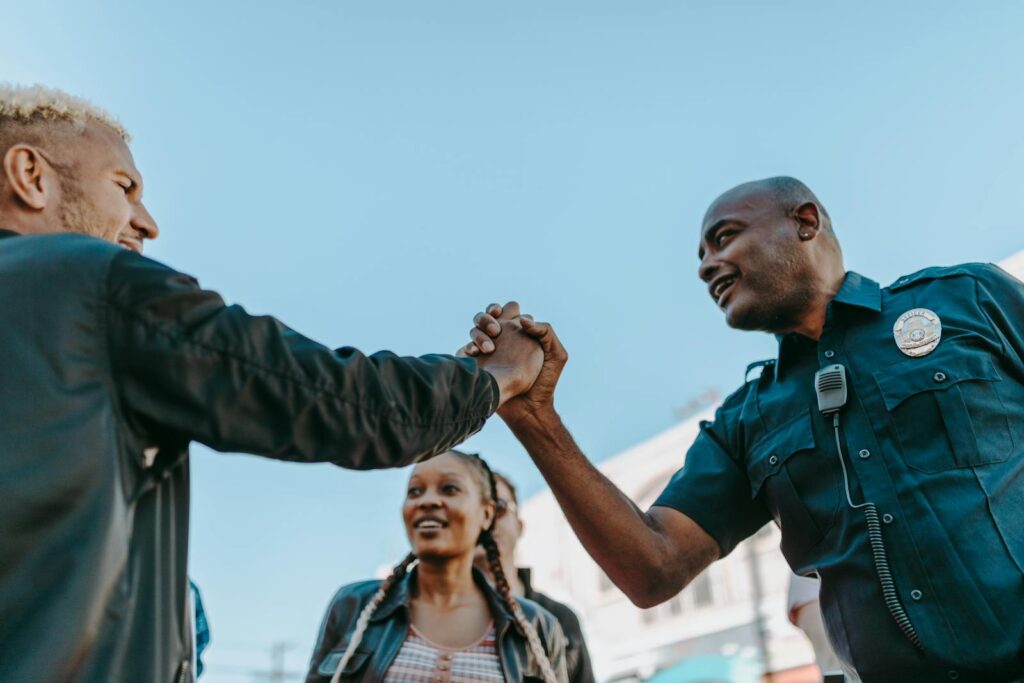 A friendly handshake between a police officer and a civilian during an outdoor community event.