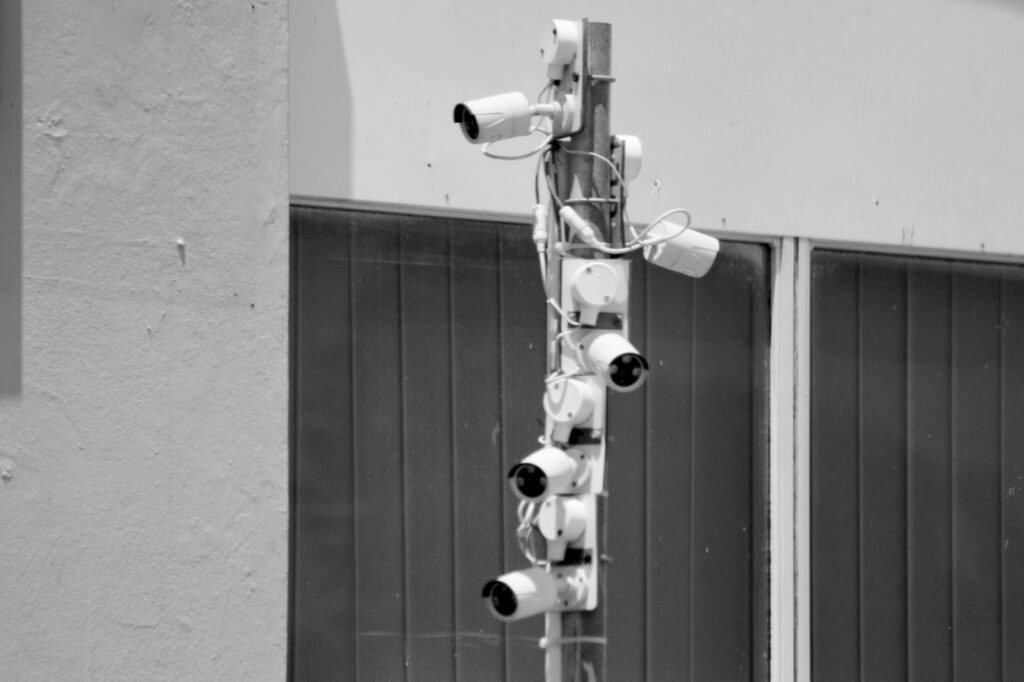 a black and white photo of security cameras on a pole